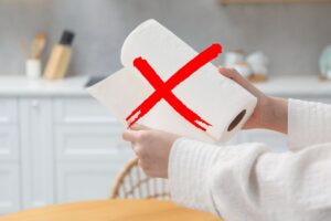 donna con in mano carta assorbente cucina ed x rossa